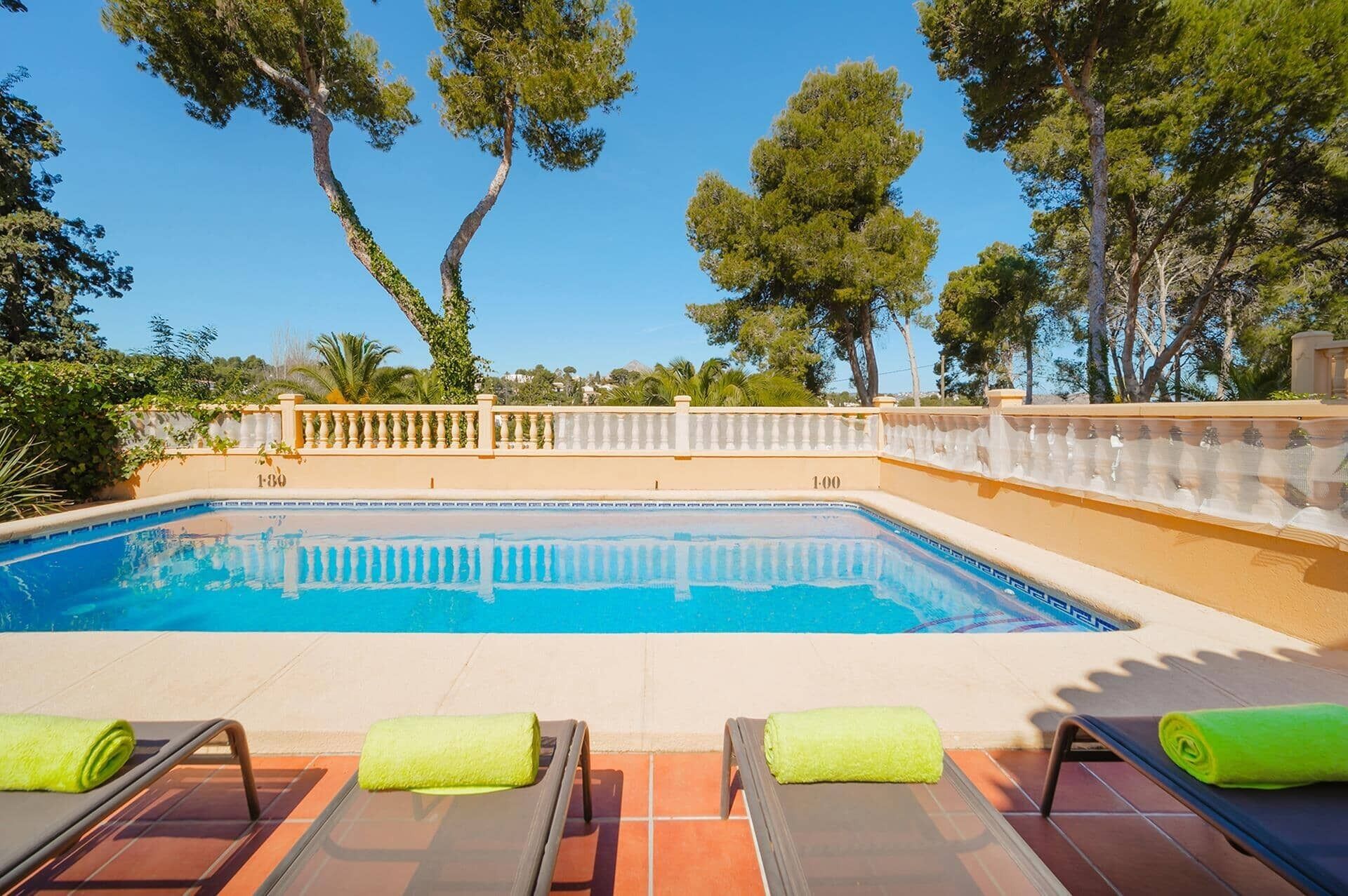 A swimming pool with lounge chairs and a fence.