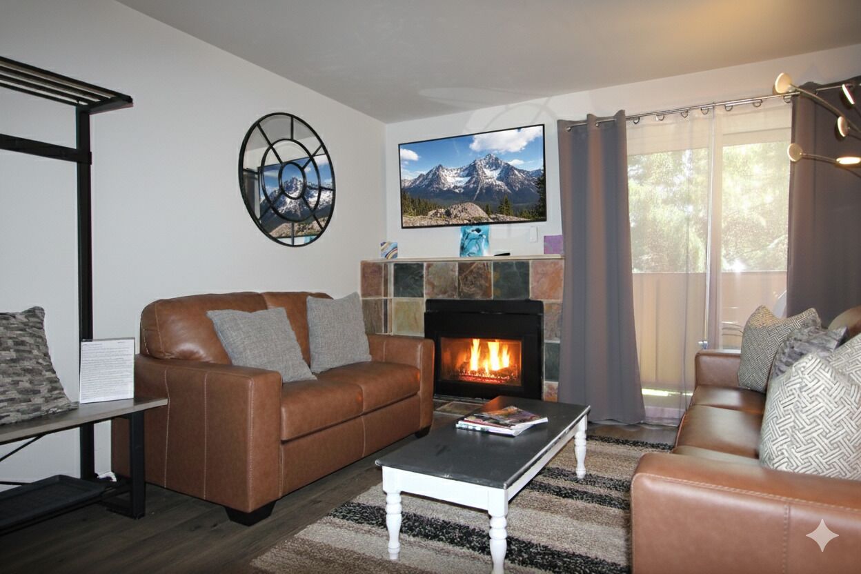 A living room with a fireplace, leather sofas, a coffee table, and a television.