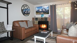 A living room with a fireplace, leather sofas, a coffee table, and a television. - Renovated Condo steps from the Beaver Creek shuttle! (Avon)