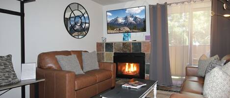 A living room with a fireplace, leather sofas, a coffee table, and a television.