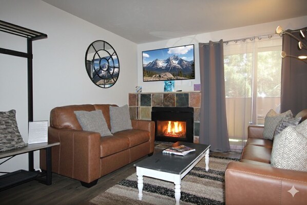 A living room with a fireplace, leather sofas, a coffee table, and a television. - Renovated Condo steps from the Beaver Creek shuttle! (Avon)