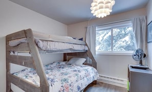 Habitación con literas, escritorio y ventilador.