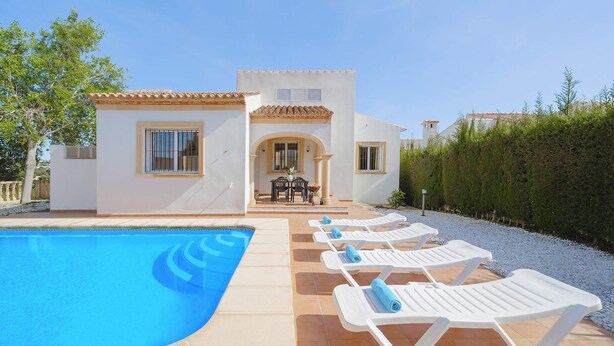 Zona de piscina con piscina, sillas reclinables blancas y terraza con mesa y sillas.