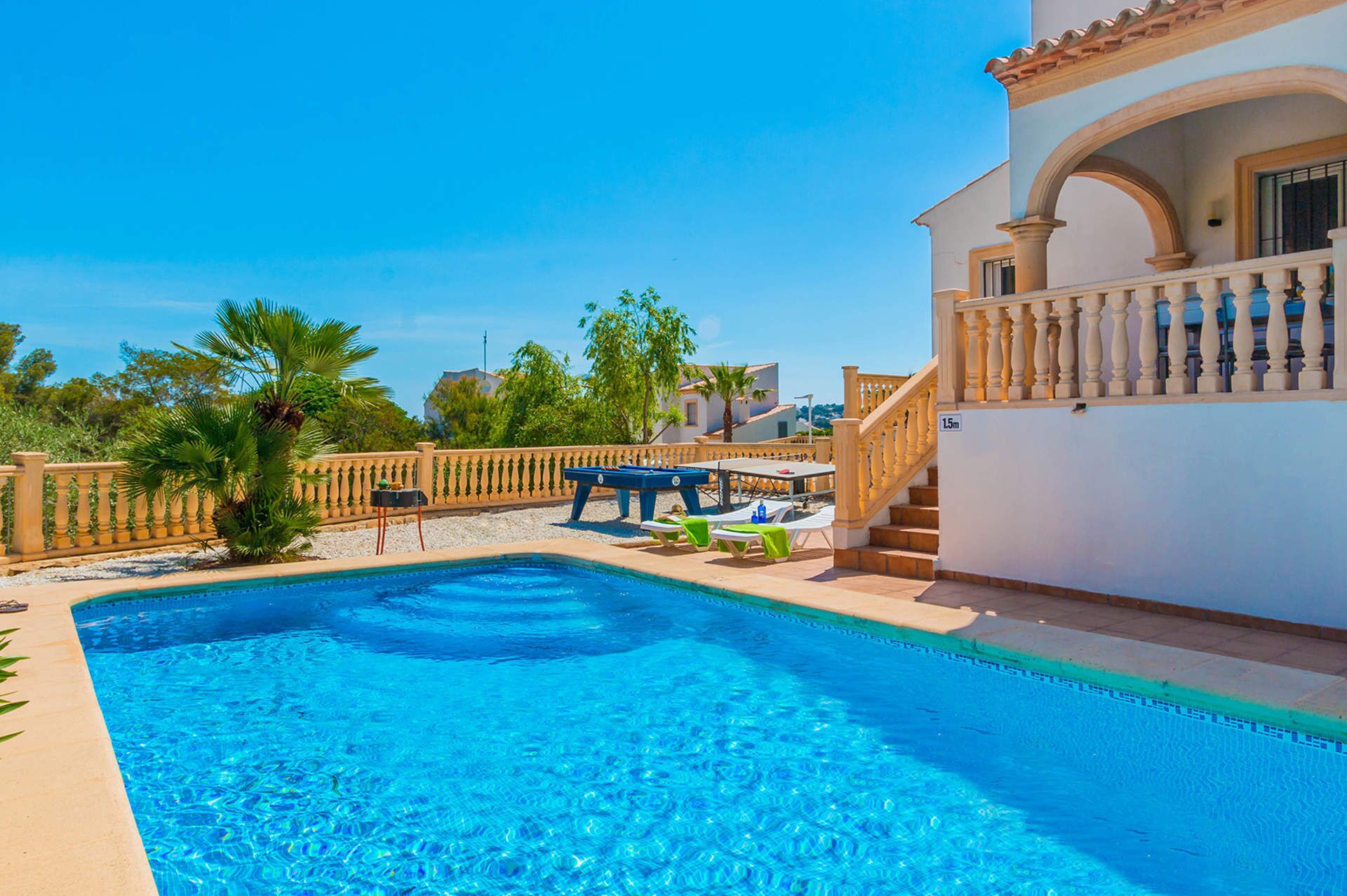 Ein Swimmingpool mit Sonnenterrasse, Liegestühlen und einer Treppe, die zu einem Balkon führt.