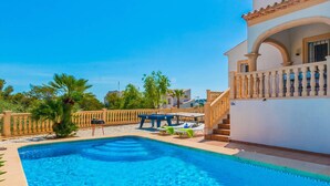 Ein Swimmingpool mit Sonnenterrasse, Liegestühlen und einer Treppe, die zu einem Balkon führt.