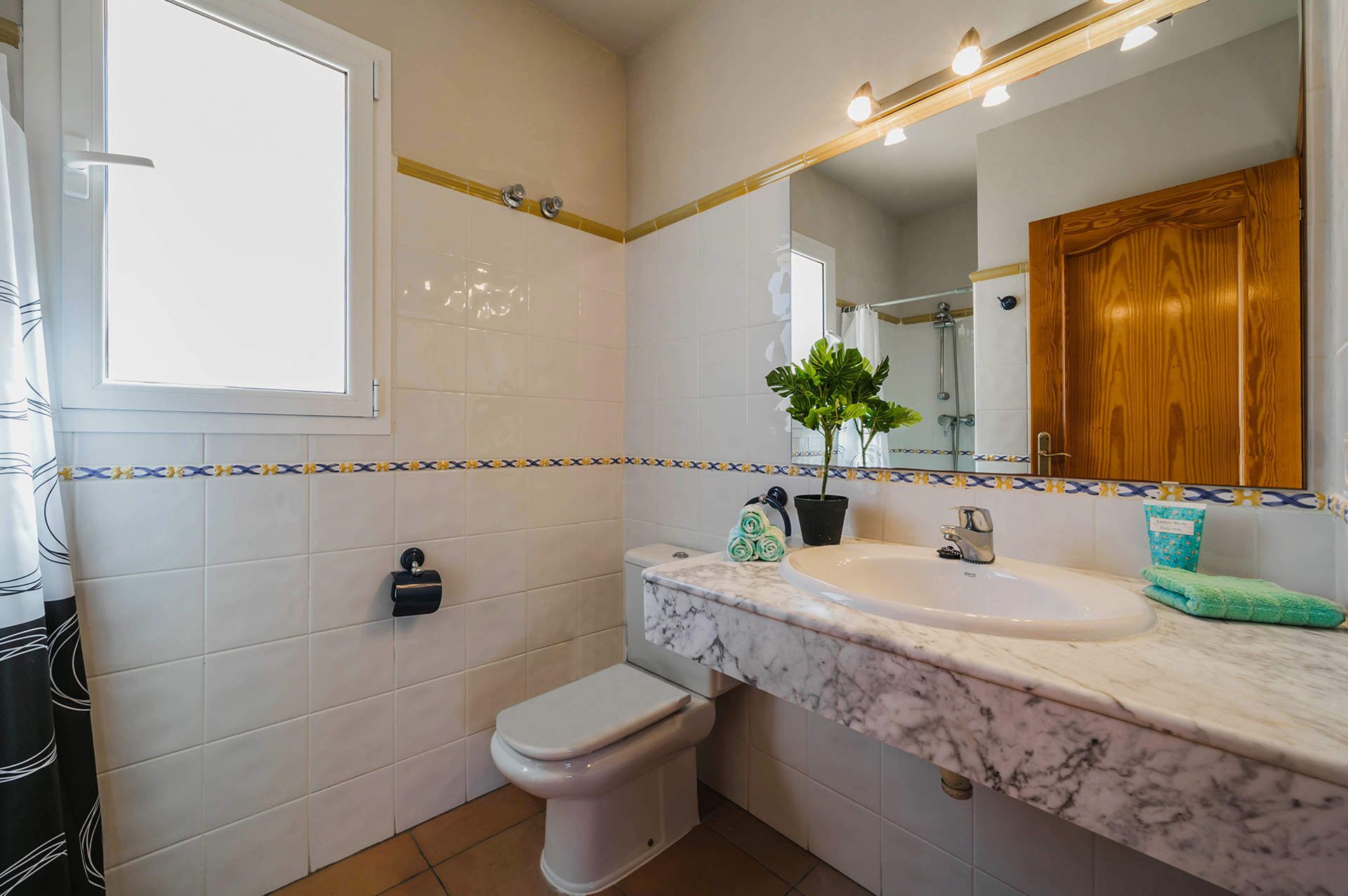A bathroom with a toilet, sink, and mirror.