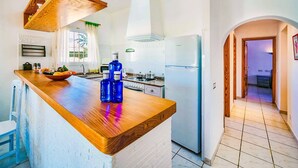 Eine moderne Küche mit einer Holz Arbeitsplatte, einem eingebauten Backofen und einem Kühlschrank.