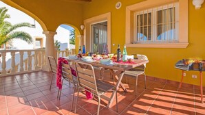 Eine Terrasse mit Esstisch, dekoriert mit verschiedenen Früchten, Flaschen und Gläsern.