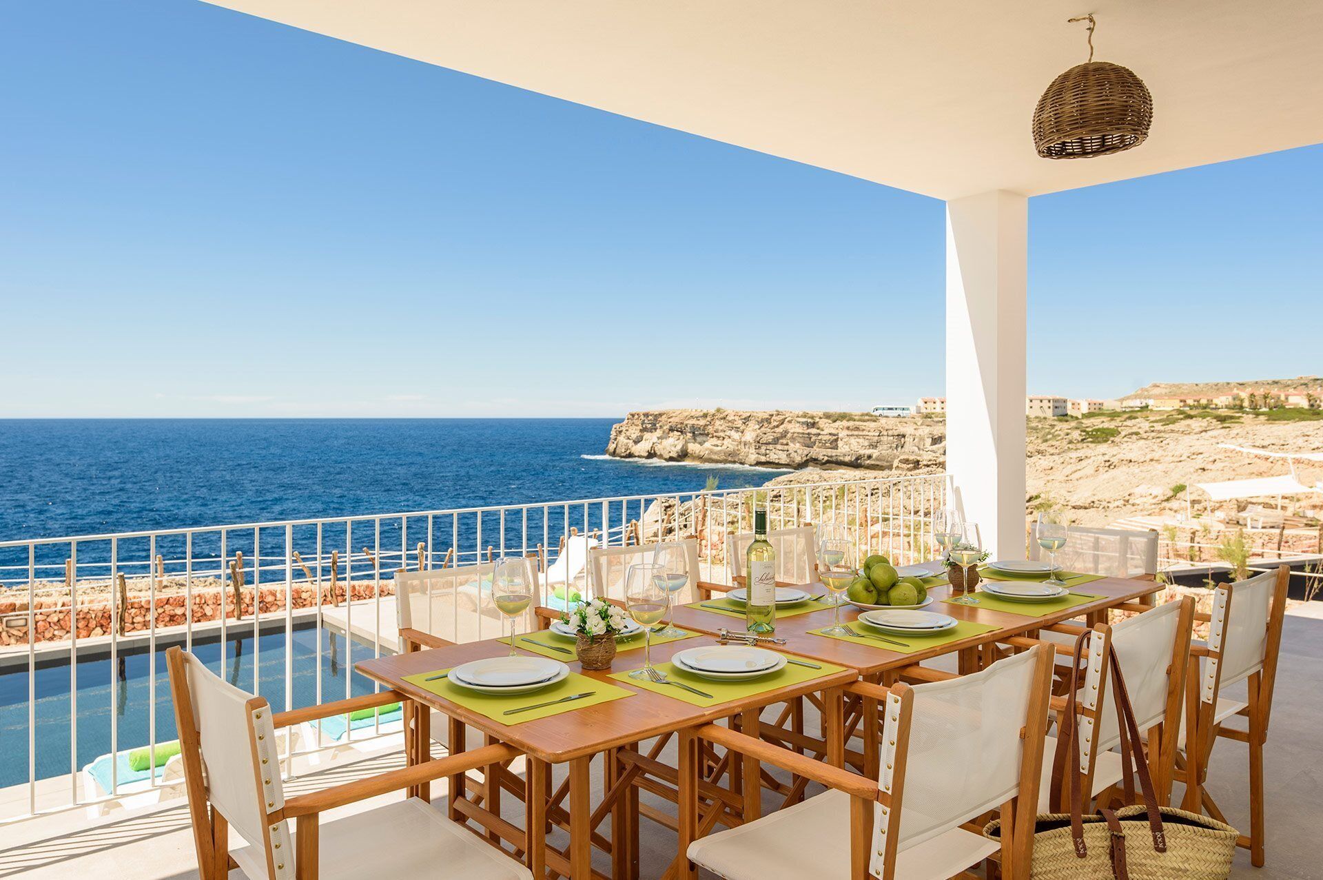 A dining area with a view of the sea and rocky cliffs.