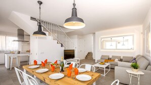 Een moderne keuken met een eethoek, witte meubels en een trap.