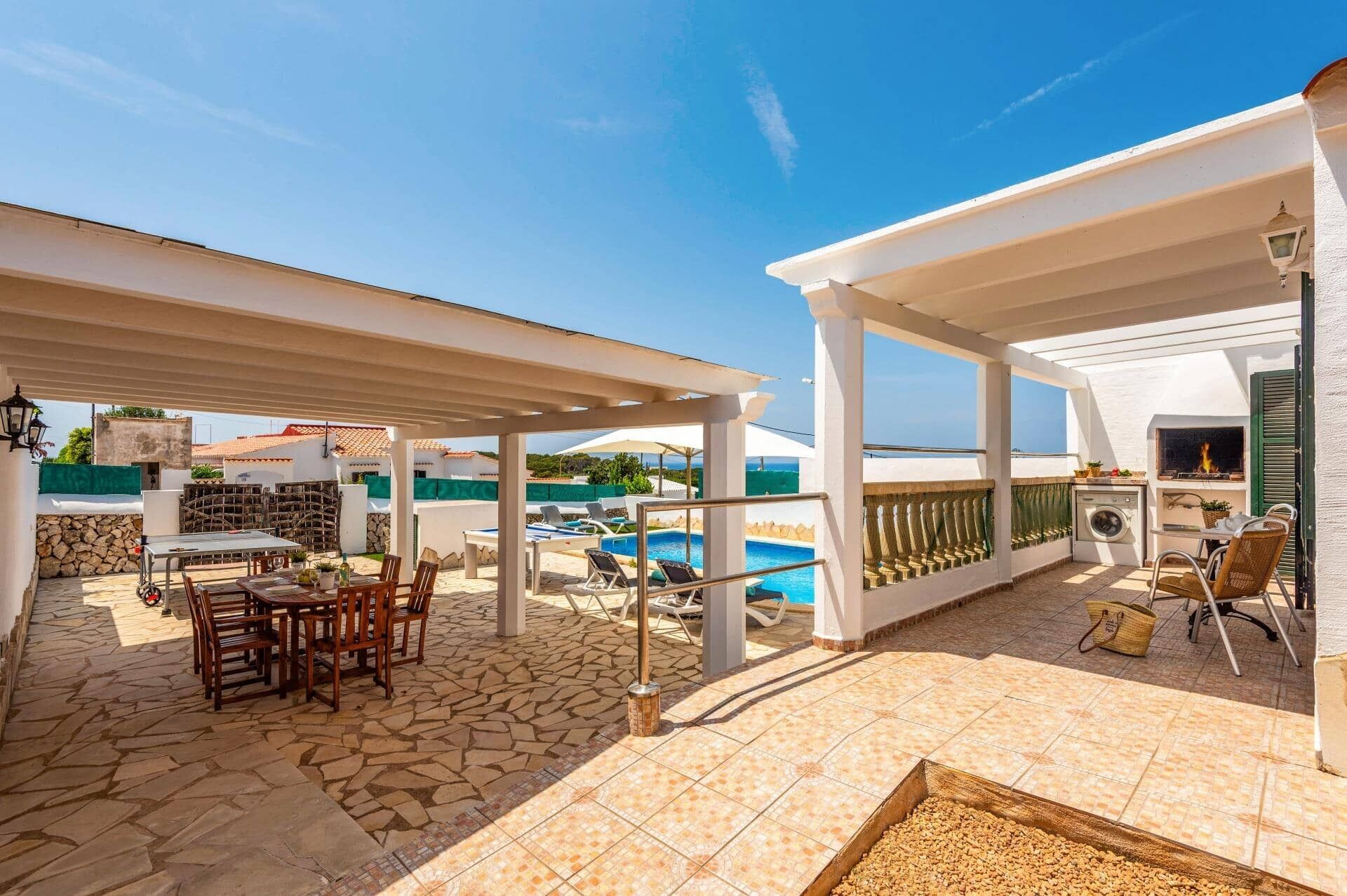 An outdoor patio with a pool, a covered seating area, and a laundry area.
