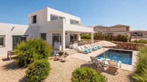 A modern two-story house with a pool, outdoor seating, and a stone wall. - Villa Amatista by Villa Plus (Los Delfines)