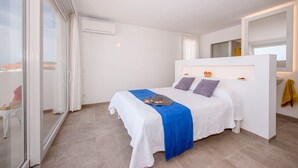 A modern bedroom with a bed, a built-in bedside table, and a large window. - Villa Amatista by Villa Plus (Los Delfines)