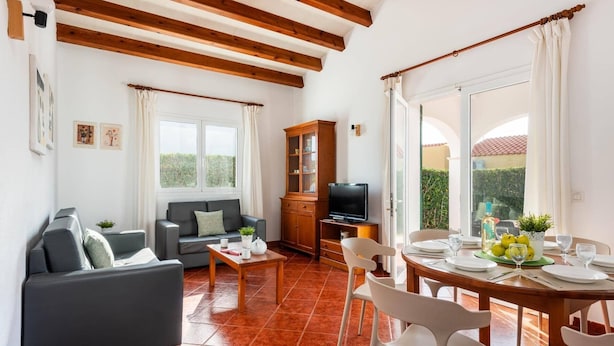 A living room with a sofa, a dining table with chairs, a television, and a cabinet. - Villa Avellano by Villa Plus (Cap d'Artrutx)