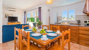 Una cucina moderna con mobili in legno, un tavolo da pranzo per quattro persone e una TV nella zona living.
