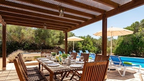 An outdoor dining area with a pergola, poolside chairs, and a pool. - Villa Biniparrell by Villa Plus (Biniparrell)