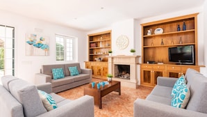 A living room with a fireplace, a television, and a bookshelf. - Villa Biniparrell by Villa Plus (Biniparrell)