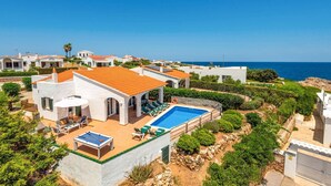 Una villa sulla costa con piscina, area salotto esterna e vista sul mare.
