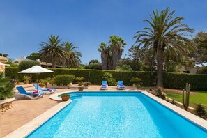A rectangular swimming pool with clear blue water, surrounded by lounge chairs and umbrellas.