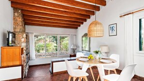 Un coin repas avec une table en bois, des chaises blanches et une cheminée en pierre.