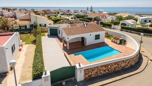 Eine Villa mit Swimmingpool, umgeben von einem gepflegten Garten und Blick aufs Meer.