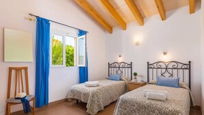 Un dormitorio con dos camas, una silla, una pizarra y una ventana con cortinas azules.