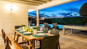 Un espacio de comedor al aire libre con una piscina al fondo.