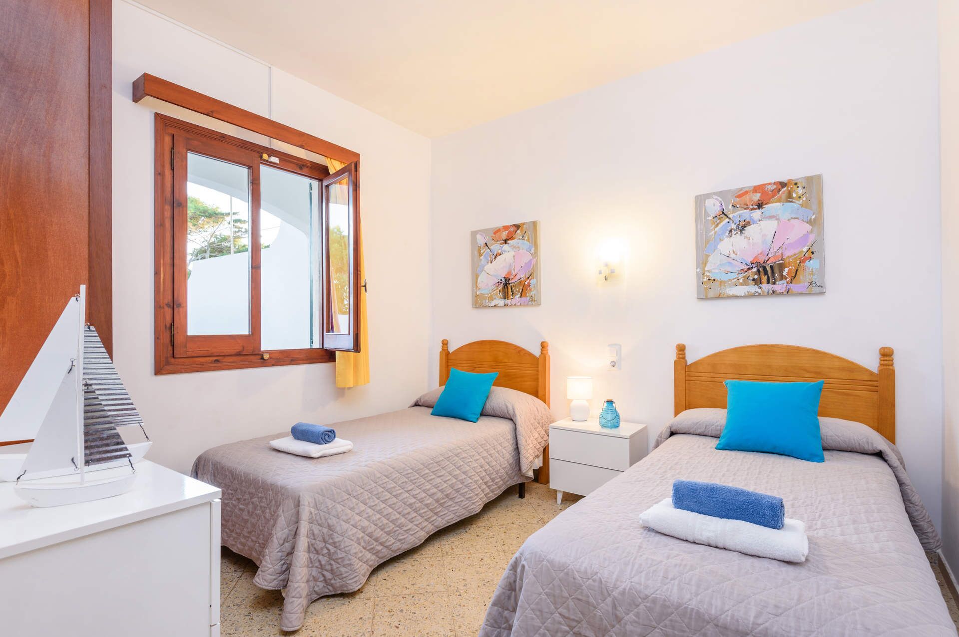 Ein Hotelzimmer mit zwei Betten, einem Fenster und Bildern an den Wänden.