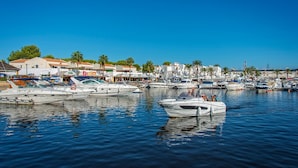 A marina with multiple boats docked, surrounded by buildings and palm trees. - Villa Imogen by Villa Plus (Cap d'Artrutx)