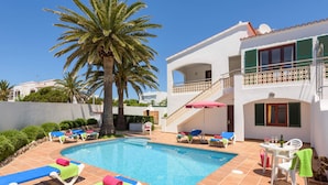 A pool area with lounge chairs and a palm tree. - Villa Imogen by Villa Plus (Cap d'Artrutx)