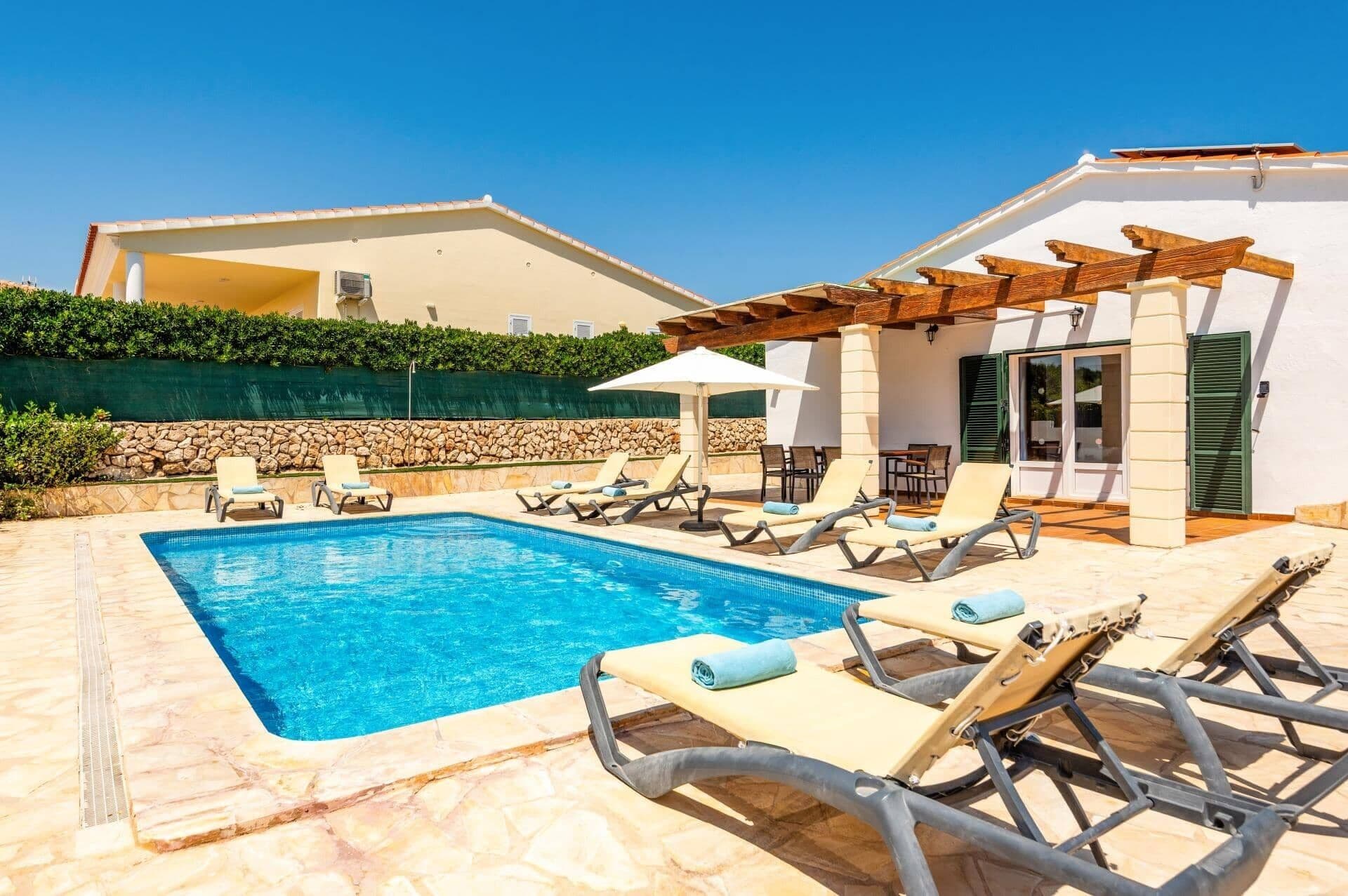 Une piscine avec des chaises longues et une pergola.