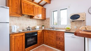 Eine kompakte Küche mit Holdekor-Schränken, einem Backofen, einem Geschirrspüler und einem Fenster für natürliches Licht.
