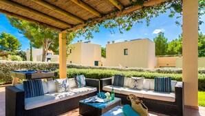 Un patio al aire libre con mobiliario de mimbre, una mesa de billar y una zona de estar cubierta.
