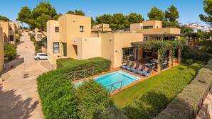 Zona residenziale con piscina, sdraio e un viale in pietra.