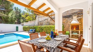 A poolside dining area with a table set for four, surrounded by wooden chairs. - Villa Las Mariposas by Villa Plus (Es Mercadal)