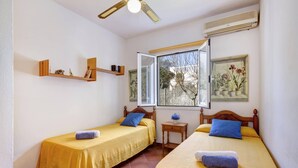 Ein Zimmer mit zwei Einzelbetten, einem Fenster mit Blick, einem Deckenventilator und einer Klimaanlage.