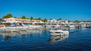 A marina with various boats docked, surrounded by buildings and palm trees. - Villa Mango by Villa Plus (Cap d'Artrutx)