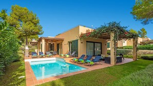 A modern house with a swimming pool, outdoor seating, and a pergola with climbing plants.