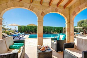 A poolside area with lounge chairs, a table with croissants and coffee, and a view of the pool. - Villa Mares by Villa Plus (Ciutadella de Menorca)