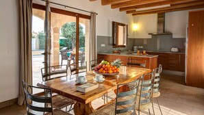 Comedor con mesa y sillas de madera, un frutero y vistas al exterior.