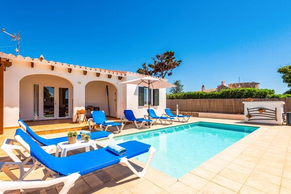 A poolside area with lounge chairs and a clear blue pool.