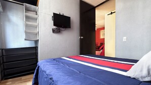 A bedroom with a bed, a TV mounted on the wall, and a wardrobe.