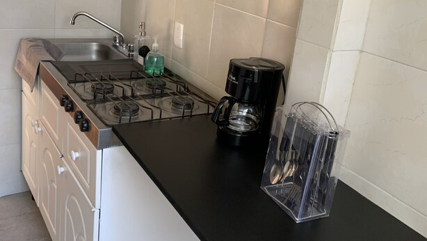 A kitchen with a gas stove, a coffee maker, and a sink.
