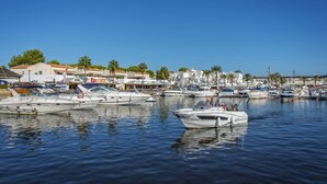 A marina with multiple boats docked, a clear sky, and buildings in the background. - Villa Noa by Villa Plus (Cap d'Artrutx)