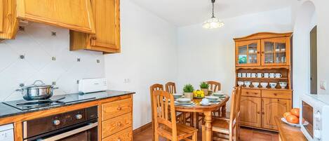 Cocina compacta con armarios de madera, una estufa y una mesa de comedor lista para cuatro comensales.