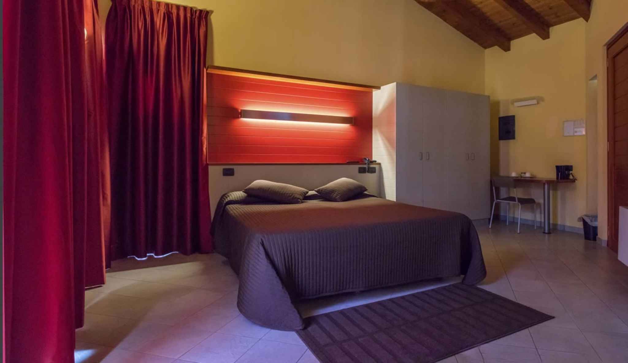 A bedroom with a bed, a desk, and a wardrobe.