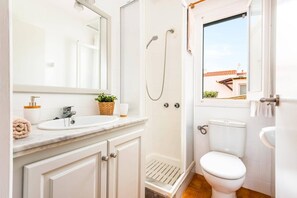 Ein Badezimmer mit Waschbecken, Spiegel, Dusche und Toilette.