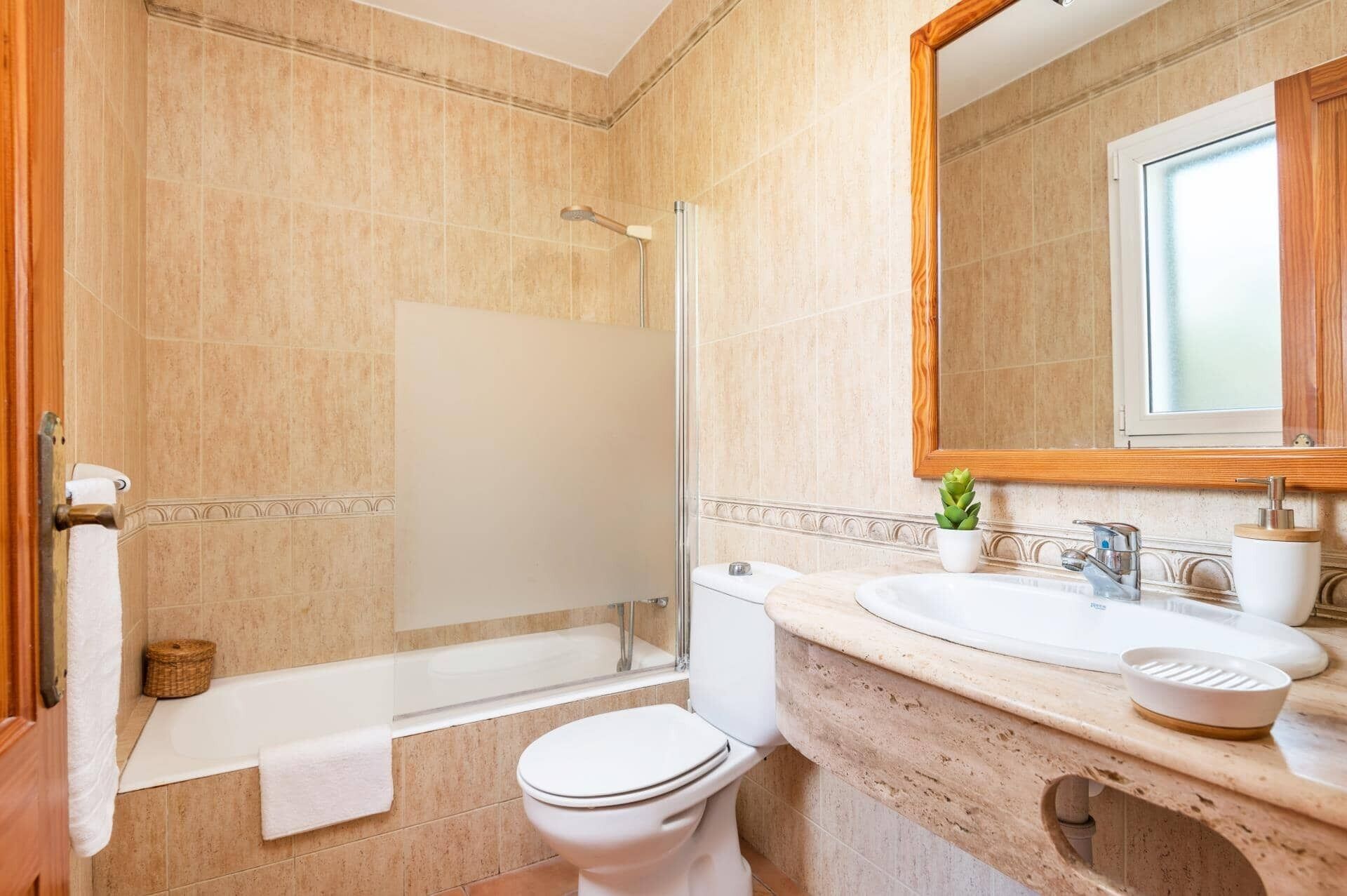 A bathroom with a bathtub, toilet, sink, and a mirror.