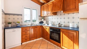 Una cocina con gabinetes de madera, lavavajillas, estufa y ventana.