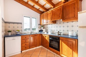 A kitchen with wooden cabinets, a dishwasher, a stove, and a window.
